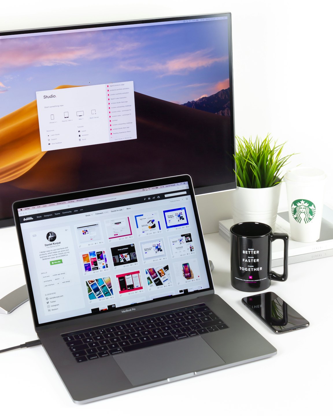 Modern creative workspace with laptop, monitor, and coffee.