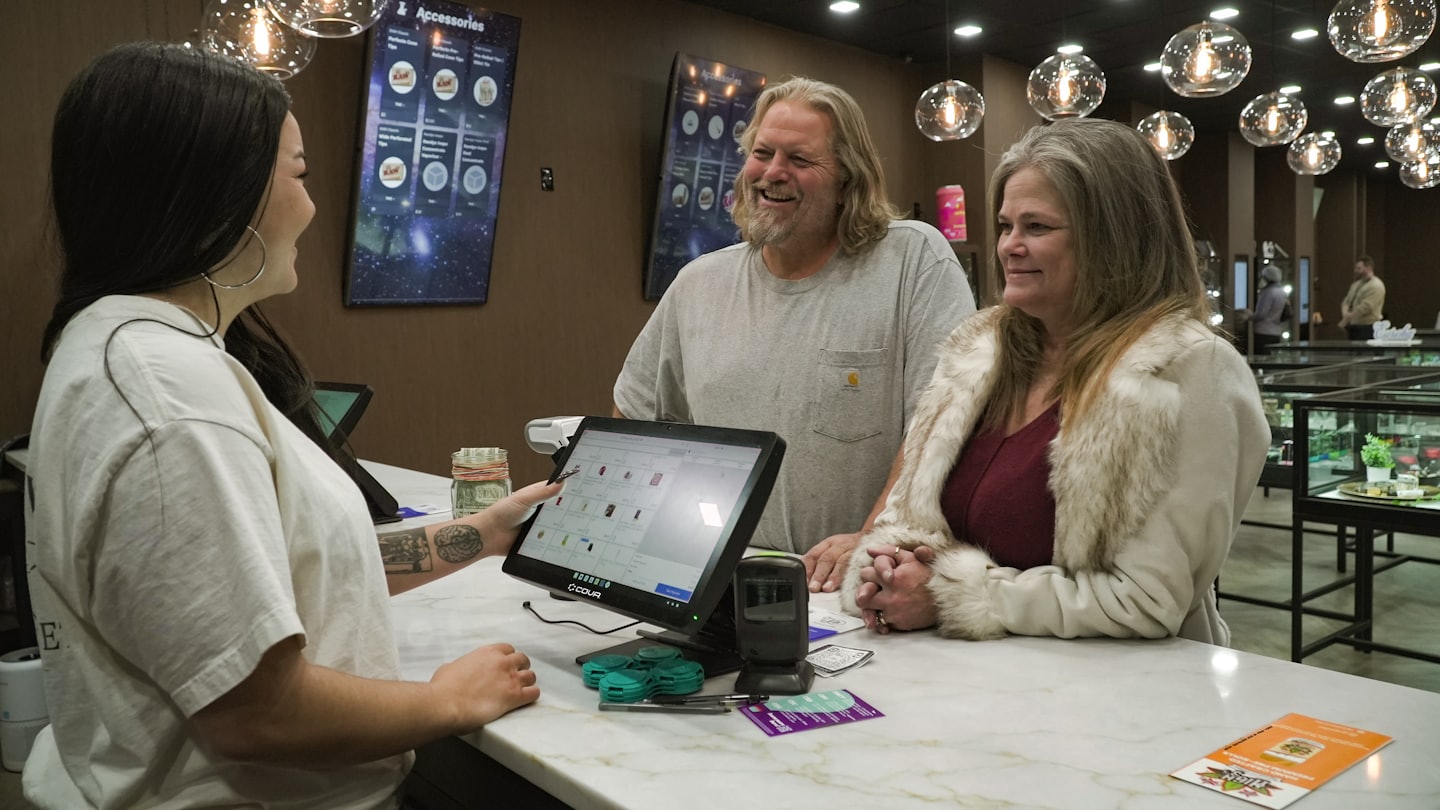 Retail employee helps customers at a digital point-of-sale screen.